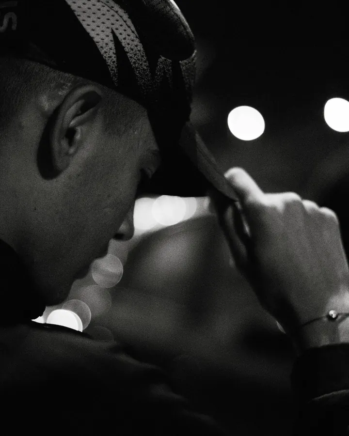 Black and white close portrait of a man pulling down his cap