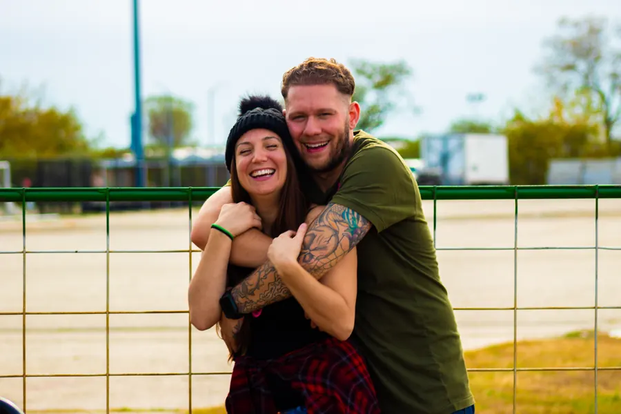 Couple laughing and hugging by a ball field