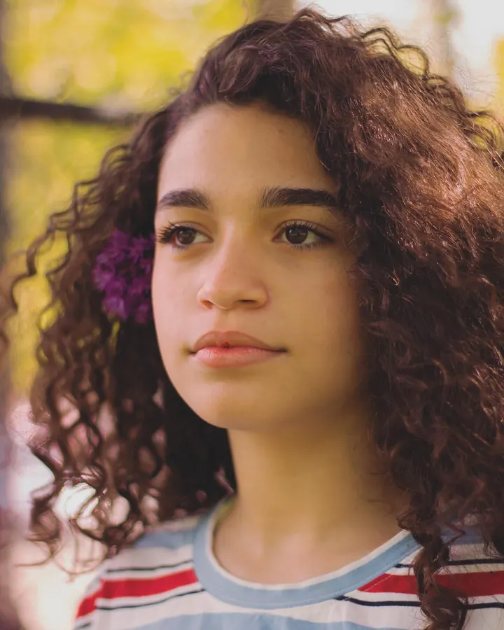 Portrait of a young woman with curly hair and a flower
