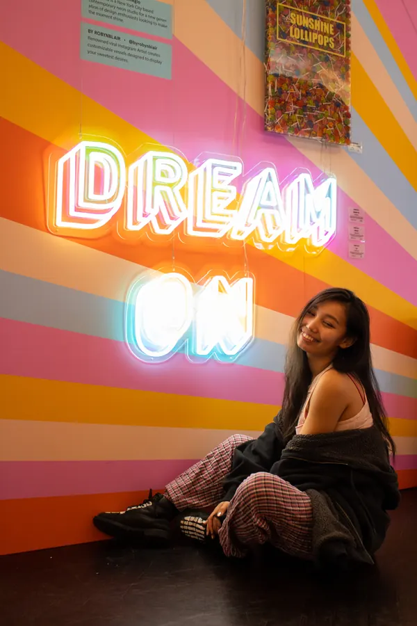 Woman sitting under a Dream On neon sign