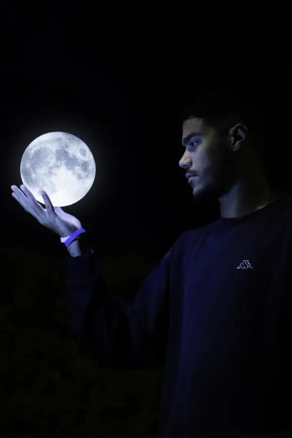 Man holding a glowing moon in his hand at night