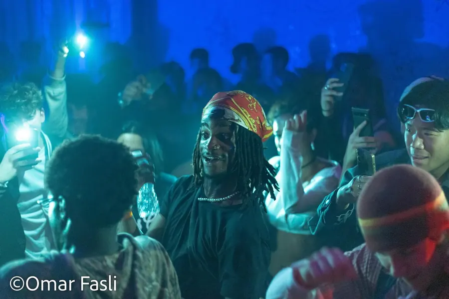 Crowd under blue light filming a performer at a show