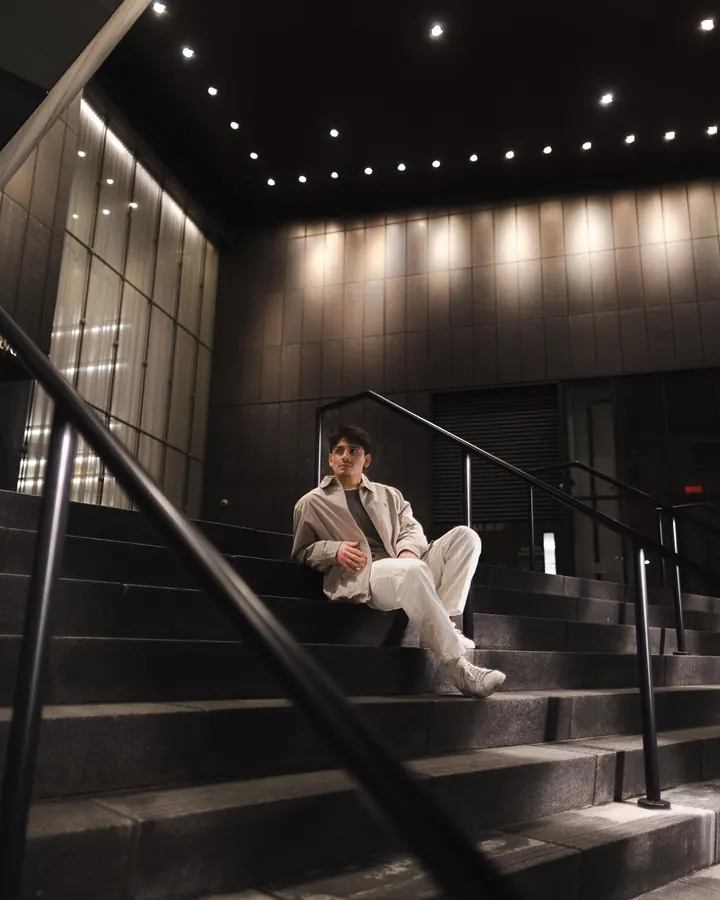 Man in a white suit sitting on a staircase at night