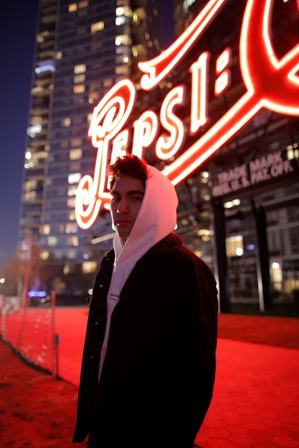Man in a white hoodie in front of the Pepsi-Cola sign in Long Island City