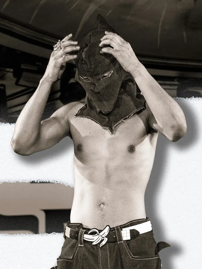 Close view of a model adjusting a black hood on the runway