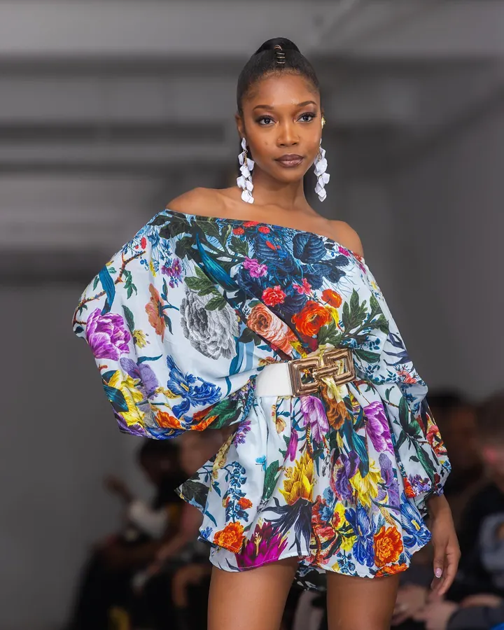 Model in a floral print dress with statement earrings on the runway