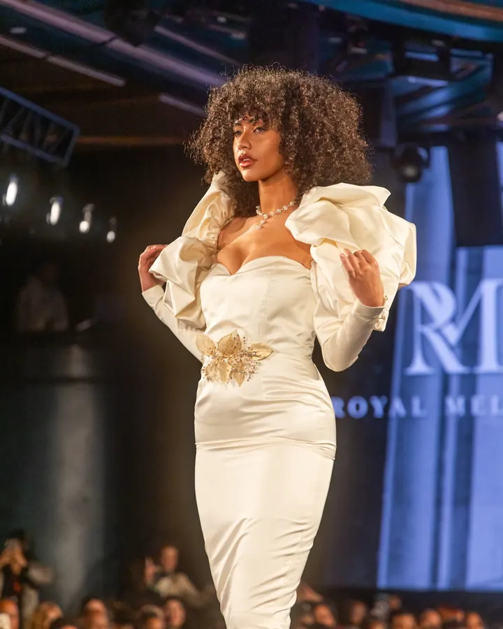 Model in a cream gown with sculpted sleeves on the runway