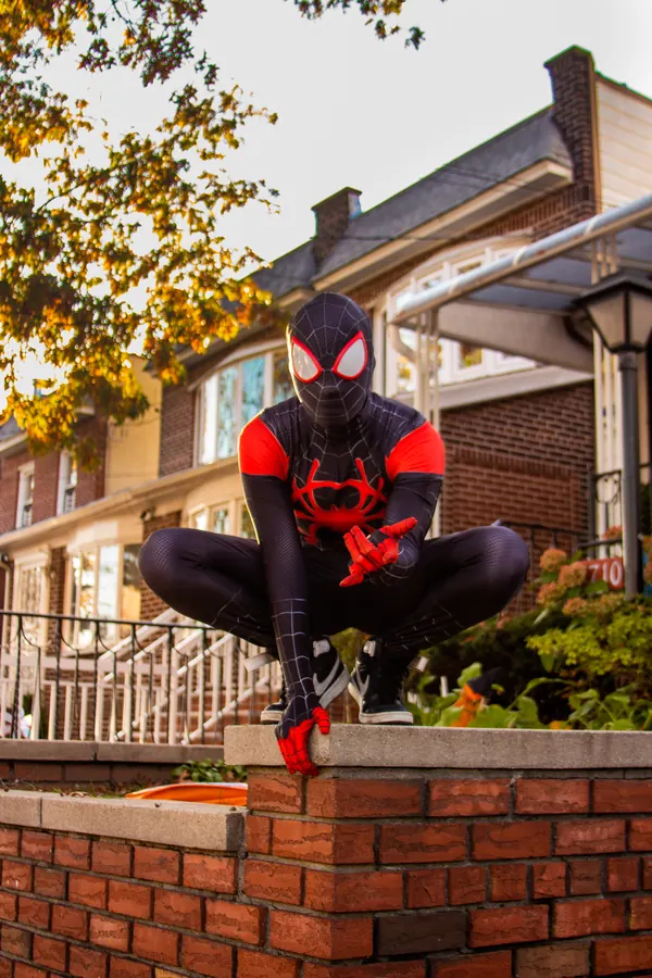 Spider-Man cosplayer crouching on a brick wall